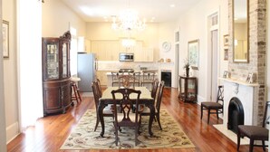 A spacious kitchen with wooden cabinets, a dining table with chairs, a chandelier, and a fireplace.