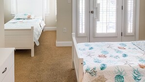 Une chambre avec deux lits, un ventilateur de plafond, une porte avec une fenêtre et un luminaire fixé au mur.
