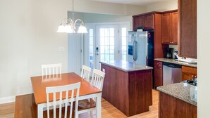 Une cuisine moderne avec des meubles en bois, un réfrigérateur en acier inoxydable et un plan de travail en granit.