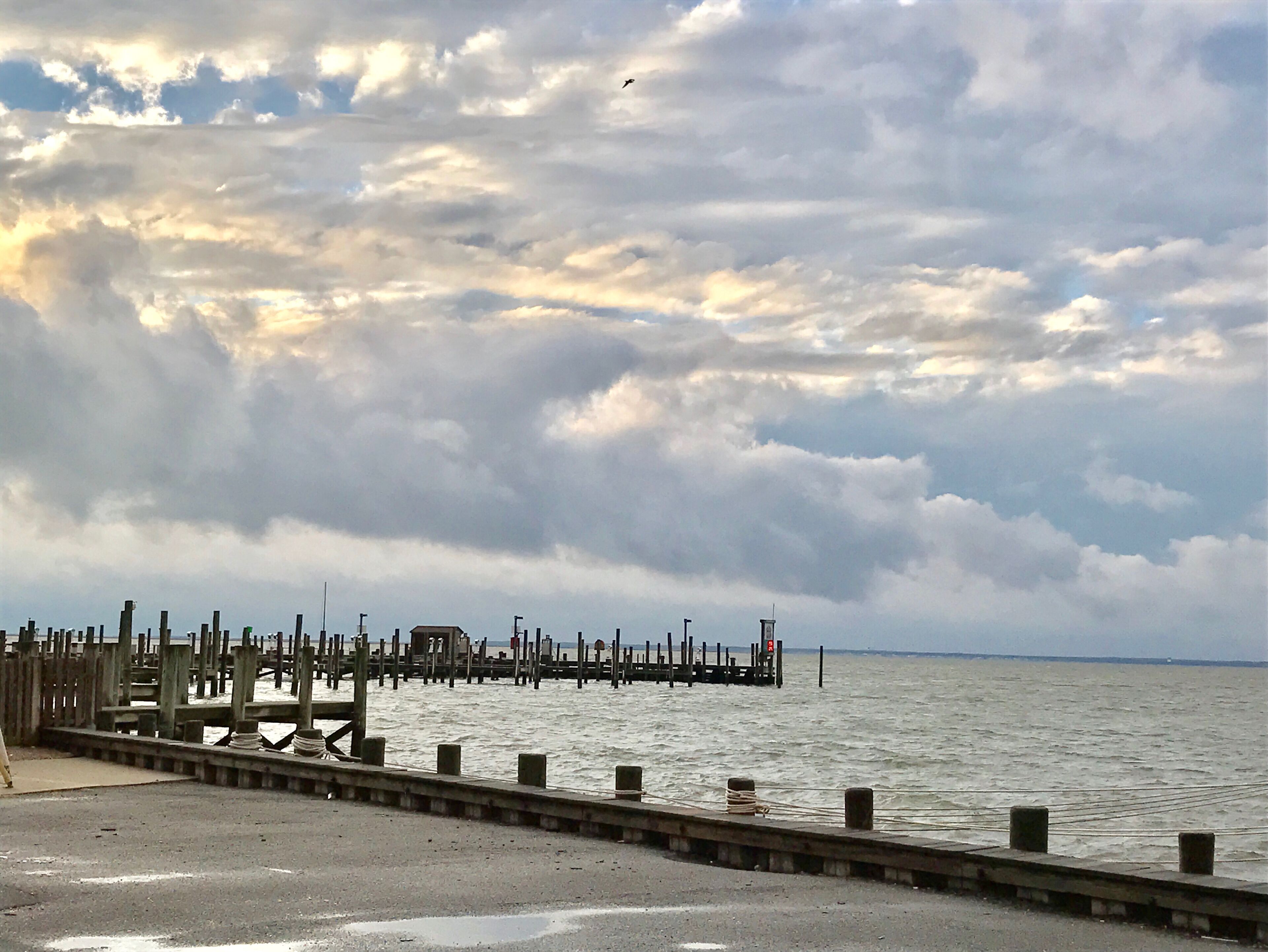 A pier extending into a body of water with a cloudy sky above.
