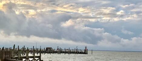 A pier extending into a body of water with a cloudy sky above.