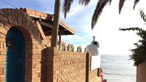 A coastal building with a blue door, brick walls, and a white bell structure.