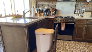 A kitchen with a built-in trash can, a stove, and a coffee maker.