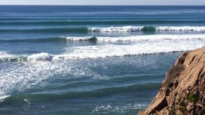 A coastal scene with waves crashing onto a rocky shore.