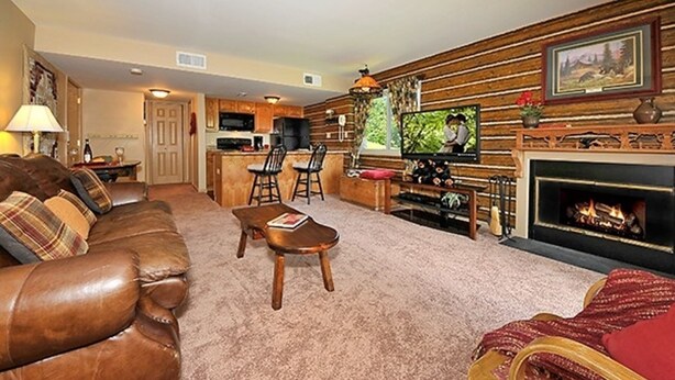 A living room with a brown leather sofa, a wooden coffee table, and a fireplace. - Magnificent Moutain View Studio. Sleeps up to 4      (Gatlinburg)