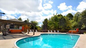 A swimming pool with lounge chairs, a covered seating area, and trees in the background. - Magnificent Moutain View Studio. Sleeps up to 4      (Gatlinburg)