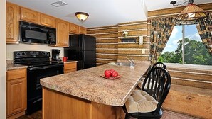 A kitchen with wooden cabinets, a granite countertop, a black refrigerator, and a sink. - Magnificent Moutain View Studio. Sleeps up to 4      (Gatlinburg)