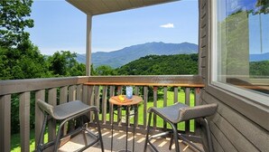 A covered outdoor area with two chairs and a small table, overlooking a mountainous landscape. - Magnificent Moutain View Studio. Sleeps up to 4      (Gatlinburg)