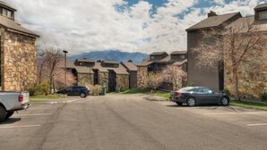 A residential street with stone and wood buildings, parked cars, and mountains in the background. - Magnificent Moutain View Studio. Sleeps up to 4      (Gatlinburg)