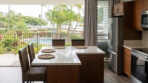 A kitchen with a dining area, a view of a pool, and a balcony.