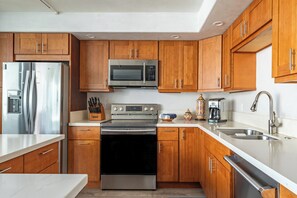 A modern kitchen with stainless steel appliances, wooden cabinets, and a marble countertop. - South Kihei Condo Steps from Kam III Beach w/ Ocean View (Kihei)