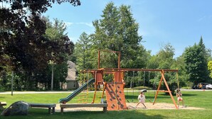 Un parque infantil con tobogán, estructuras de escalada y columpios.