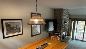 Una mesa de comedor de madera con un candelabro, un televisor montado en la pared y una pared de piedra.