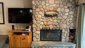Una sala de estar con chimenea de piedra, televisor de pantalla plana y mueble de madera para entretenimiento.