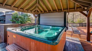 Een hottub onder een houten terras met een overdekte patio.