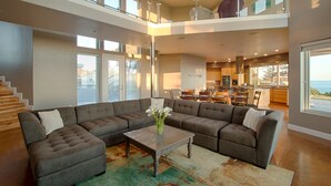 Amplia sala de estar con un sofá modular, una mesa de centro y vistas al área de cocina y comedor.