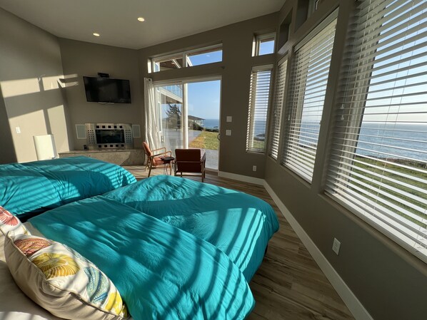Un dormitorio con dos camas, televisión, una silla y ventanas amplias con persianas.