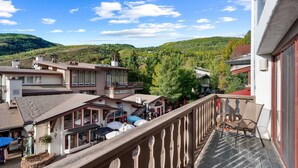 A hotel with a balcony overlooking a village and mountains.