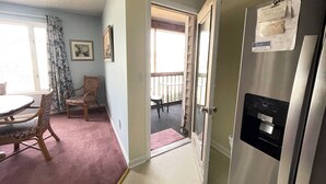 A room with a dining table, chairs, a refrigerator, and a door leading to a balcony. - 3 bedroom Family Friendly condo (Lewes)