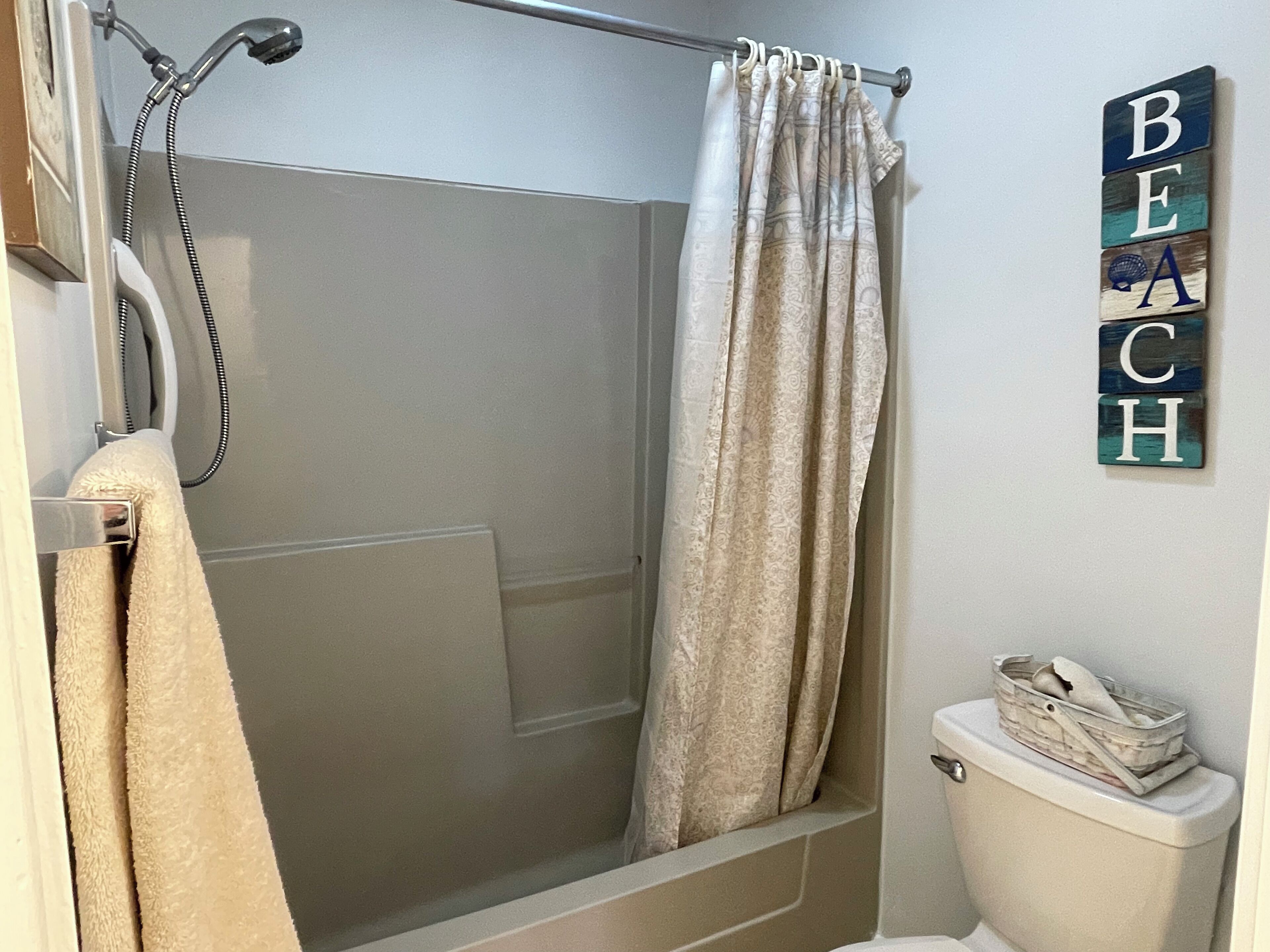 A bathroom with a shower, a toilet, and a towel rack.