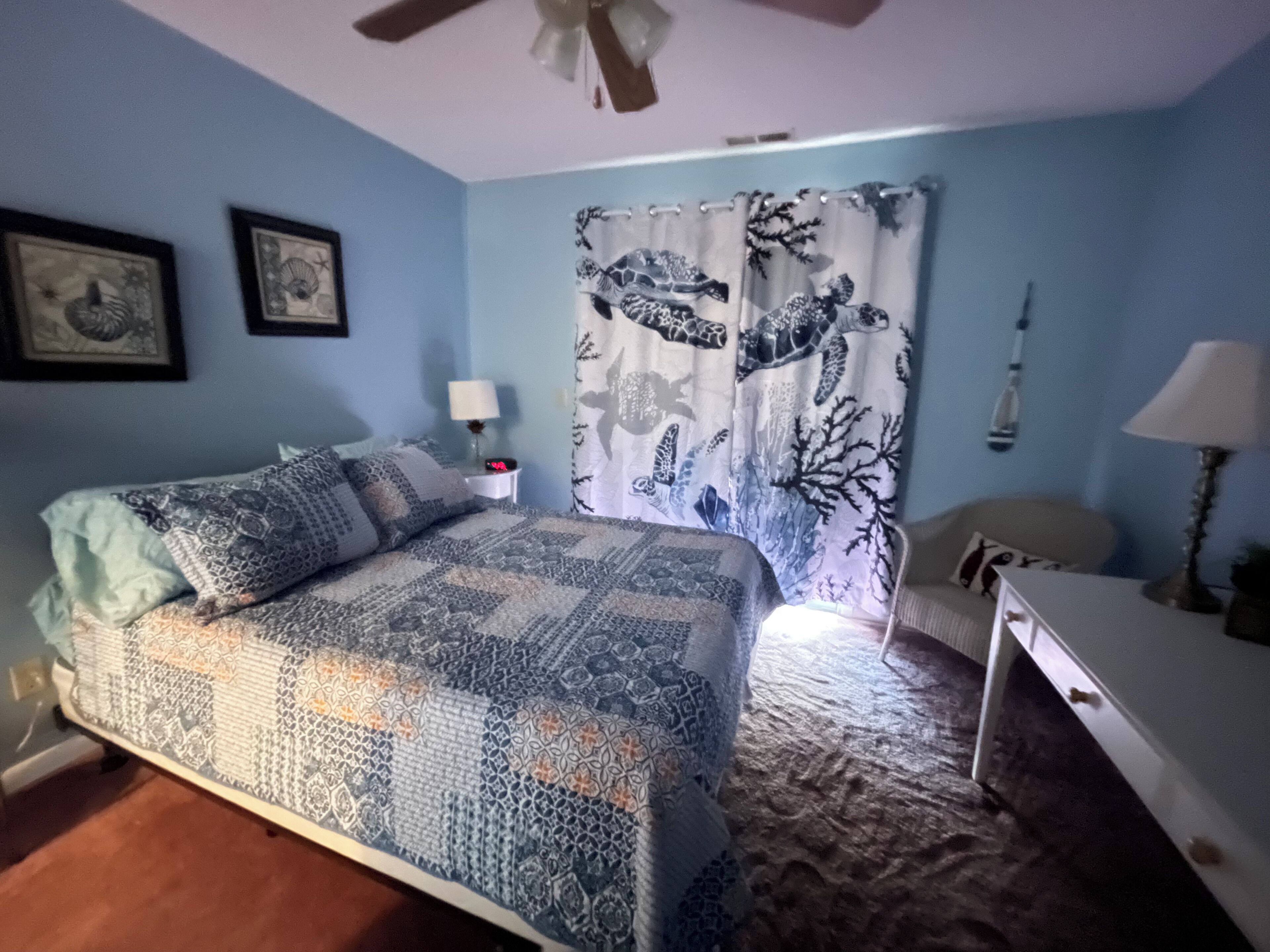 A bedroom with a bed, a nightstand, a chair, and a desk.