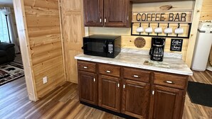 A kitchen with wooden cabinets, a coffee bar sign, a microwave, and a coffee maker. - The Smoky Mountains are OPEN FOR BUSINESS. Recently remodeled on inside.  (Sevierville)