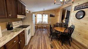 A wooden interior with a kitchen, dining area, and a clock on the wall. - The Smoky Mountains are OPEN FOR BUSINESS. Recently remodeled on inside.  (Sevierville)