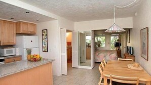 Ett rymligt kök med ett matbord och stolar i trä, ett kylskåp och en mikrovågsugn.