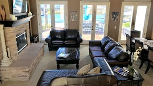 A living room with a fireplace, leather sofas, a coffee table, and a dining area with a table and chairs.