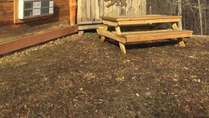 A rustic cabin with a wooden deck and a bear cutout on the wall. - The Mountaineer Rustic Yurt (Genoa)