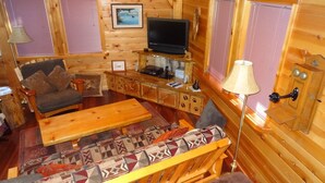 A cozy cabin interior with a sofa, a coffee table, a TV, and a wooden cabinet. - Red Blanket Cabin Near Crater Lake National Park (Prospect)