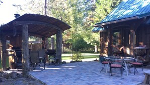 An outdoor patio with a covered seating area, a barbecue grill, and a table with chairs. - Red Blanket Cabin Near Crater Lake National Park (Prospect)