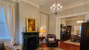 Un salon avec une cheminée, un canapé, une table basse et un coin repas agrémenté d’un lustre.