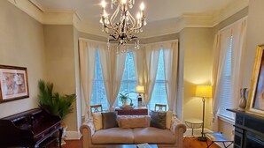 Un salon comprenant un piano, un canapé, une table basse et un lustre.