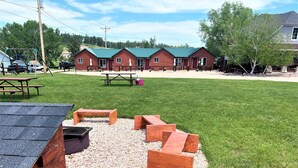 Un camping con cabañas de madera, mesas de picnic y una zona de barbacoa.