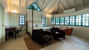 Une chambre à coucher avec un grand lit, deux fauteuils, un bureau et une baignoire.