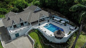 A large house with a swimming pool, a covered patio, and a lush garden. - Luxury 4 Bedroom Tobago Villa, Ocean View, Large Pool, Cabana (Mt. Irvine)