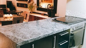 Una cocina moderna con encimera de granito, electrodomésticos de acero inoxidable y armarios oscuros.