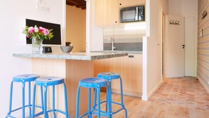 A kitchen with wooden cabinets, a microwave, and a sink. There are blue stools and a vase with flowers on the counter. - LATIN QUARTER, WOODEN BEAMS, 30–60 days ahead? Ask for a private offer. C2-VAs (Paris)