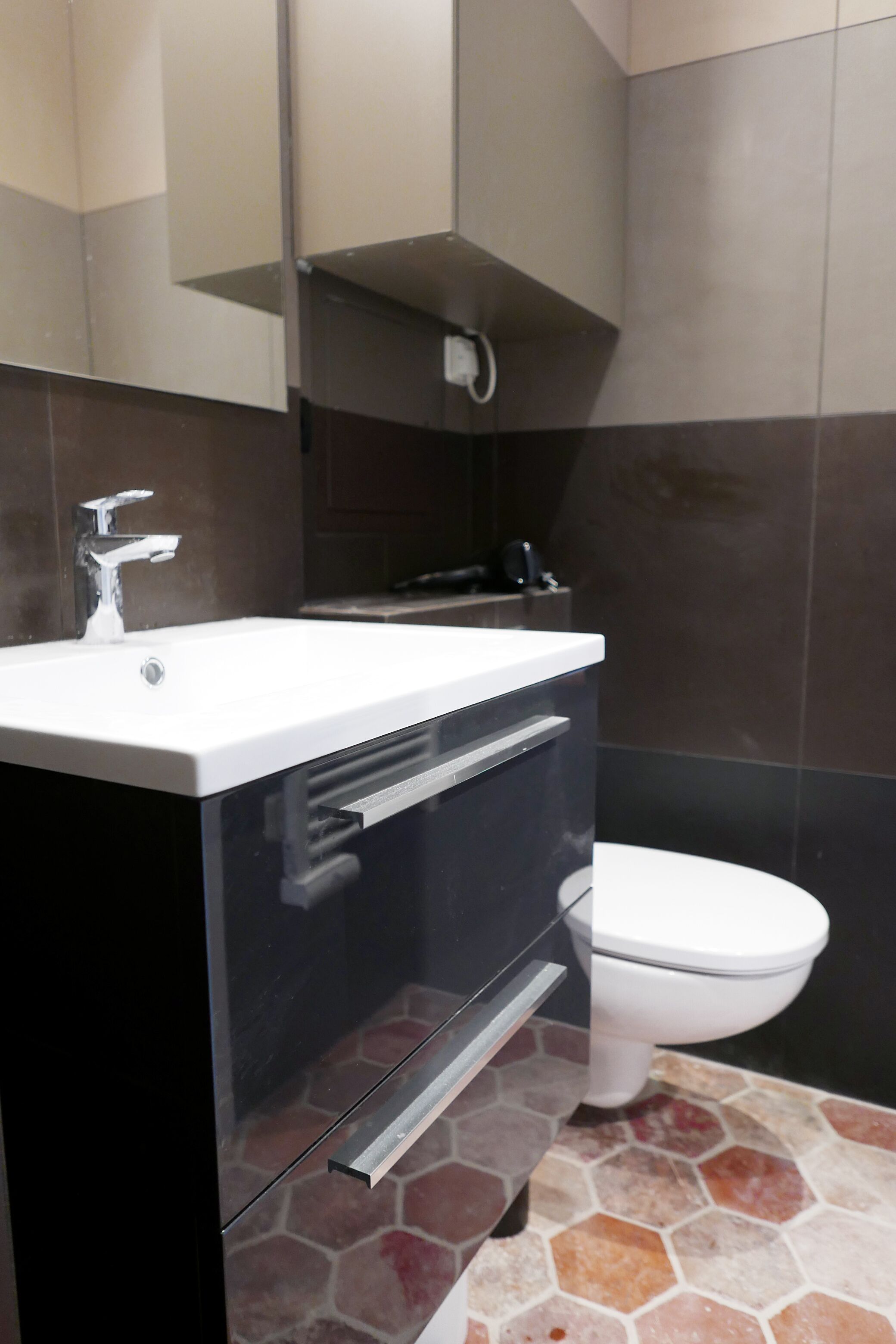 Un baño moderno con un lavabo blanco, un mueble negro y un inodoro blanco.