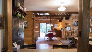 A wooden interior with a dining area, kitchen, and a view of the outdoors. - Adventure U.P- Lake House on Lake Michigan (Rapid River)