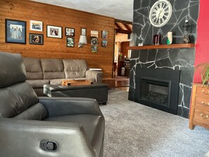 Ein Wohnzimmer mit Kamin, Holzwänden, einer Couch und einem Couchtisch.