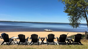 A lakeside view with chairs and tables, a dock, and a clear sky. - Adventure U.P- Lake House on Lake Michigan (Rapid River)