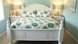 A neatly made bed with a patterned bedspread, two bedside tables with lamps, and a wall with a single piece of artwork.