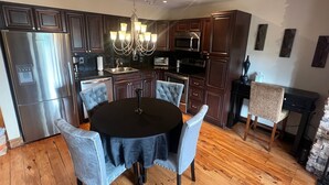 Une cuisine moderne avec des meubles en bois foncé, des appareils électroménagers en acier inoxydable et un lustre.