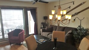 Un salon avec une table ronde, des chaises, un canapé, un ventilateur de plafond et un lustre.