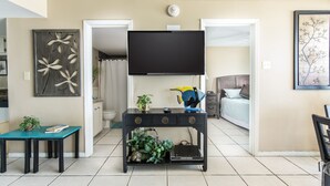 Un salon moderne avec un téléviseur à écran plat, une table basse agrémentée d’objets décoratifs et un canapé.