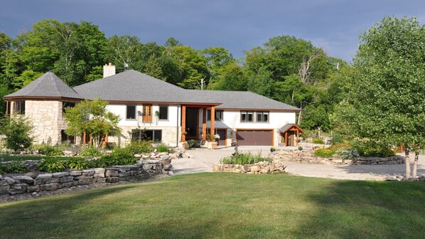 A two-story house with a stone facade, a grey roof, and a well-maintained lawn. - Guest bedroom in Quarry House (Fish Creek)