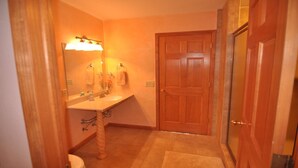 A bathroom with a wooden door, a sink with a mirror, and a towel rack.
