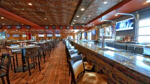 A restaurant with a long counter, multiple tables, and chairs.